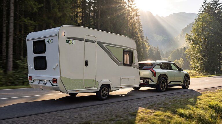 Next Wohnwagen im Abendlicht, gezogen von einem kompakten Elektroauto
