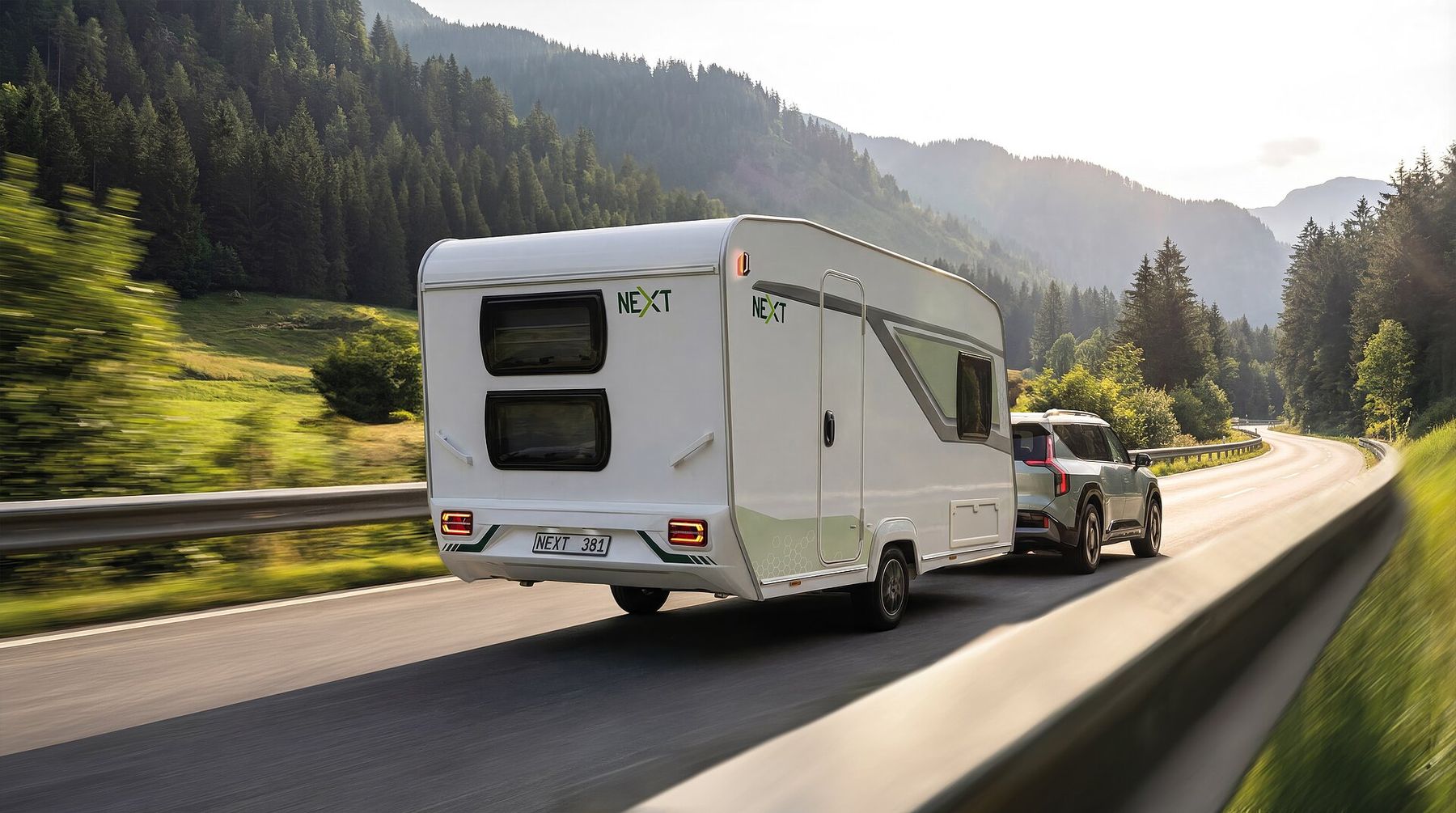 Next Wohnwagen wird von einem Elektro-SUV durch die Berge gezogen